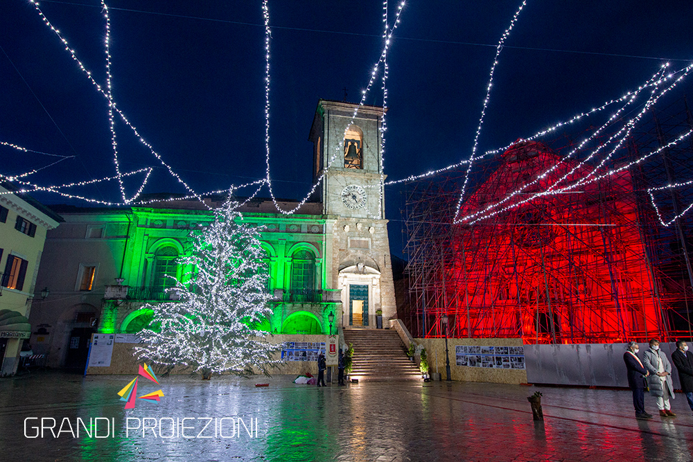 Piazza del campanile di norcia illuminata con i colori del tricolore italiano e con luminarie natalizie